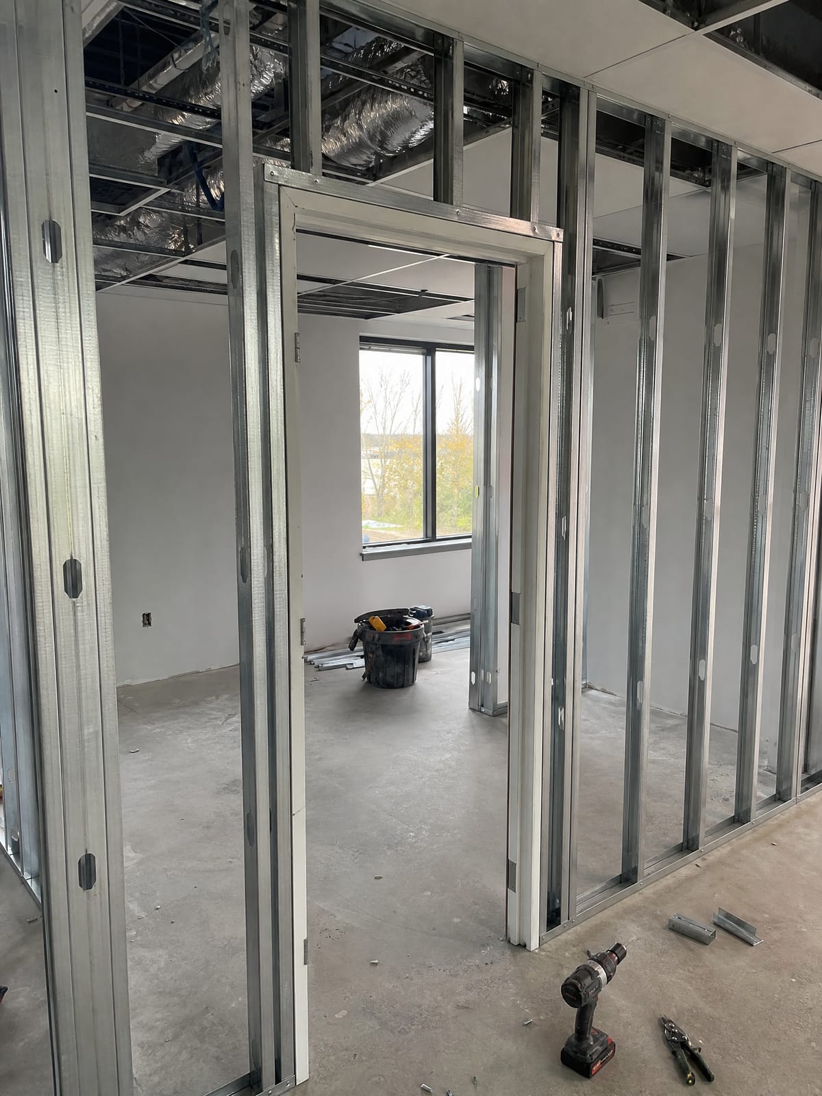 Metal stud partition wall framing mid-construction with a door opening cut into the frame