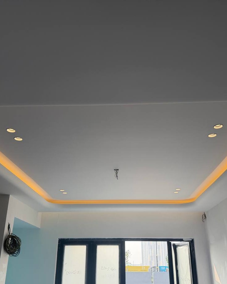 Plaster Ceiling Drop with LED Cove Lighting – Klang Residence Recessed rectangular plaster ceiling drop with warm yellow LED cove lighting and multiple downlights, Klang residence installation, unfinished walls and pending window grille below