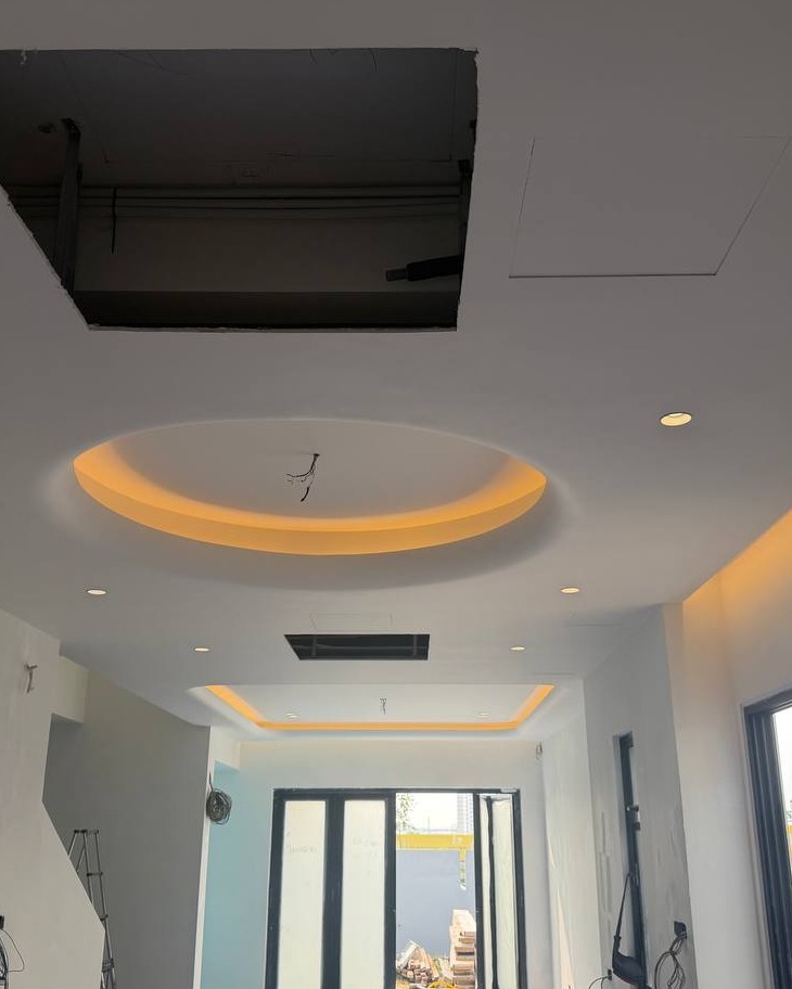Circular Cove Lighting Ceiling Detail – Klang Residence Round plaster ceiling cove with hidden LED light trough and recessed downlights in Klang residence hallway, showing unfinished access panel cut for electrical wiring overhead