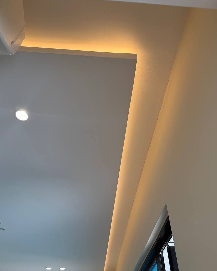 Plaster Ceiling Cove Lighting Detail – Rawang Plaster ceiling drop with concealed cove lighting along ceiling-to-wall corner in Rawang residential ground floor home, warm LED strip highlighting curved plaster edge beside recessed downlight