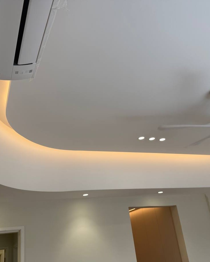 Curved Plaster Ceiling Drop with LED Strip Lighting - Rawang Curved plaster ceiling drop with warm LED strip lighting and recessed downlights, installed around a wall-mounted air conditioning unit in a Rawang home