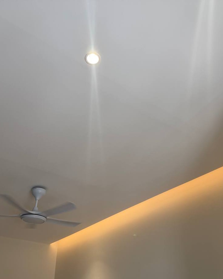Plaster Ceiling with Curved Cove LED Lighting - Rawang Flat plaster ceiling in Rawang home with recessed spotlight and warm LED strip lighting tracing a curved cove edge, ceiling fan mounted nearby