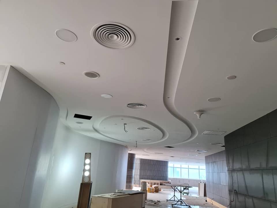 Curved plaster ceiling with round ventilation outlets in commercial office