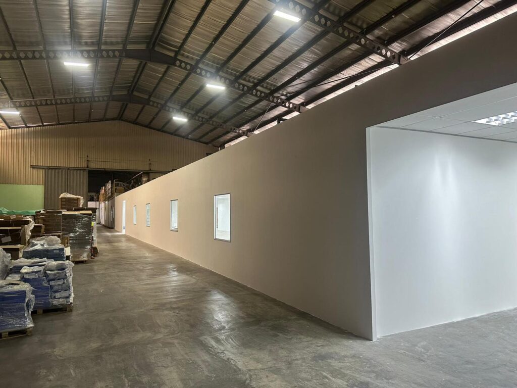 Completed full-length partition wall built to separate office and warehouse area. Smooth finish with built-in windows.