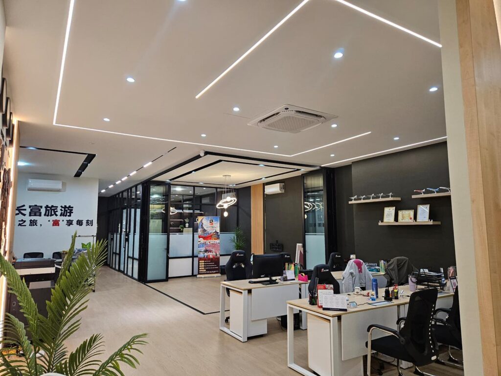 Clean and professional ceiling design with linear LED strips and downlights installed at a Kepong travel agency office. Enhancing workspace lighting aesthetics.