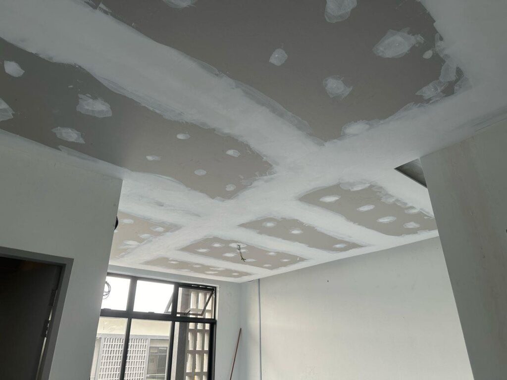 Ongoing plaster ceiling work in Setia Alam, Klang Valley. The photo shows freshly applied joint compound over screw points and board seams, part of the finishing process before paint and lighting installation.