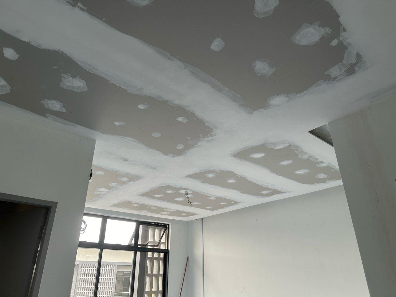 Ongoing plaster ceiling work in Setia Alam, Klang Valley. The photo shows freshly applied joint compound over screw points and board seams, part of the finishing process before paint and lighting installation.