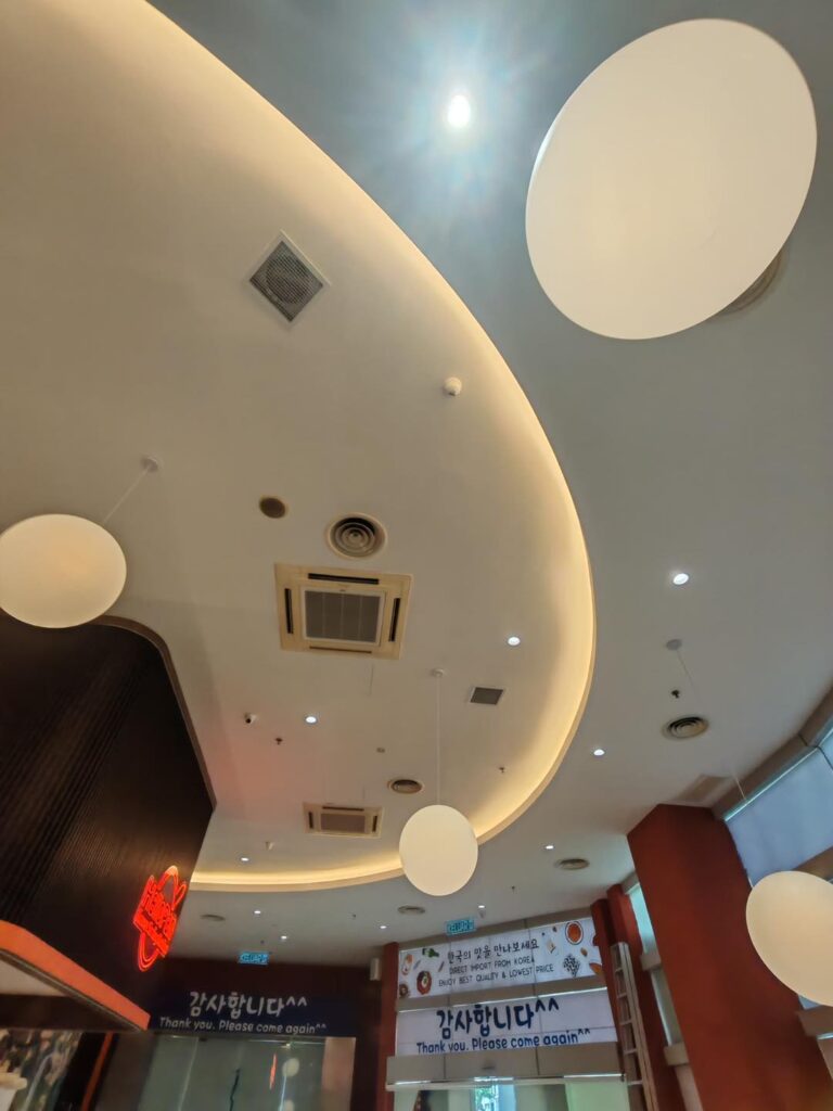 Unique commercial plaster ceiling installation in Kuala Lumpur, featuring curved layouts, round lighting panels, and cove lighting for a modern interior touch.