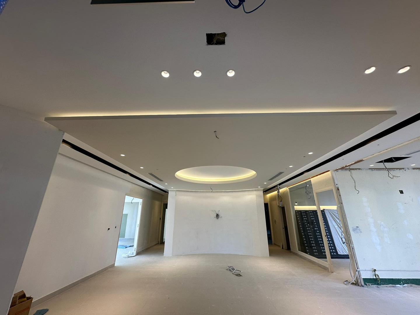 Full-room view showing a seamless integration of circular and linear plaster ceiling elements, complete with downlights and ambient LED lighting.