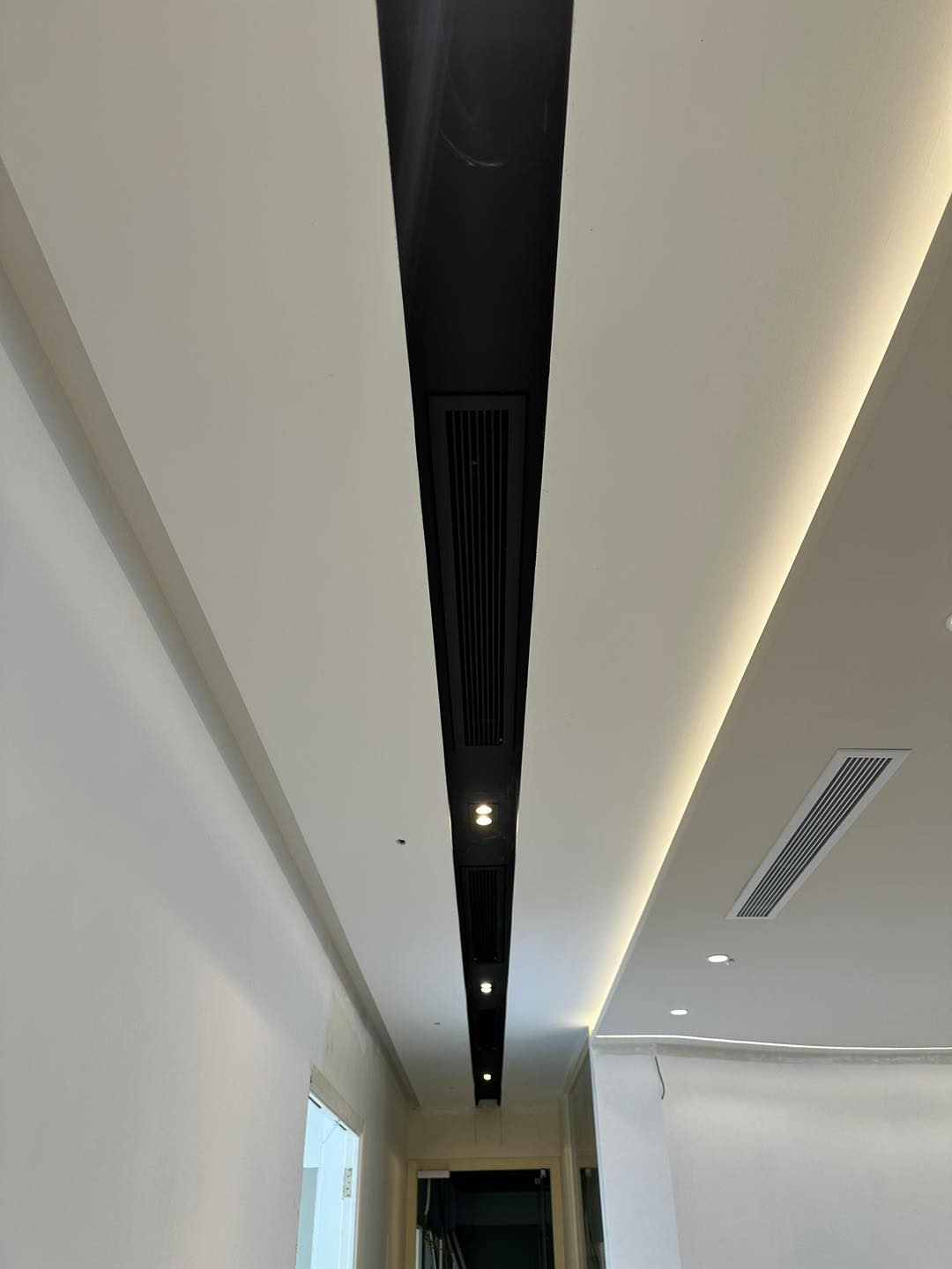 KL project completed: streamlined ceiling with black linear vent and warm LED cove lighting.