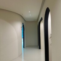Hallway with a modern plaster ceiling featuring curved arches and clean design.