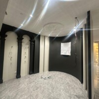 Plaster ceiling with circular design and floral wall decor in a bright corridor.