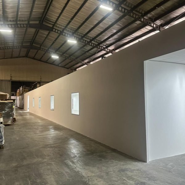 Completed full-length partition wall built to separate office and warehouse area. Smooth finish with built-in windows.