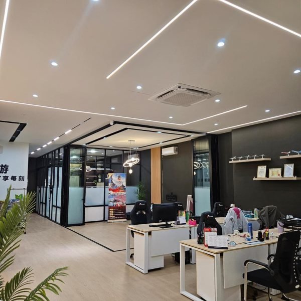 Clean and professional ceiling design with linear LED strips and downlights installed at a Kepong travel agency office. Enhancing workspace lighting aesthetics.