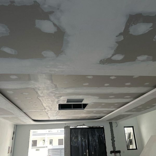 A rounded plaster ceiling centerpiece under construction, showing visible joint compound patching and an access opening. Designed to enhance room aesthetics with soft curves and future lighting integration.