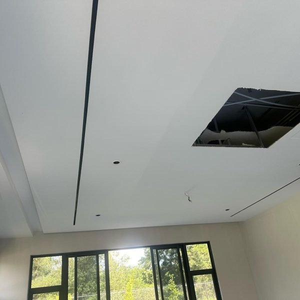 Plaster ceiling work in progress: Featuring elegant linear groove design, recessed spotlight points, and ceiling panel access for utility. Natural light enhances the contemporary finish.