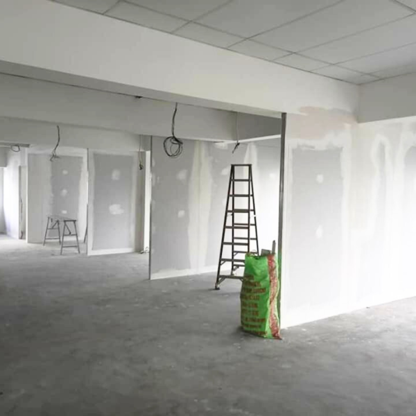 Ongoing dust-reducing partition wall setup with visible framework, ladders, and joint sealing works.