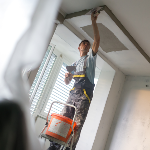 Skilled craftsman smoothing ceiling surface using professional plastering tools